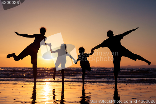 Image of Silhouette of happy family who playing on the beach at the sunse