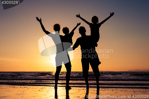 Image of Silhouette of happy family who playing on the beach at the sunse