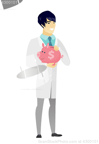 Image of Asian doctor holding a piggy bank.