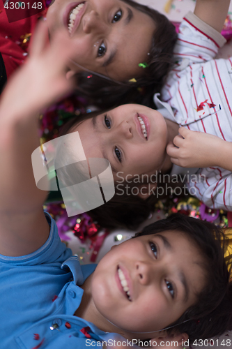 Image of kids  blowing confetti while lying on the floor