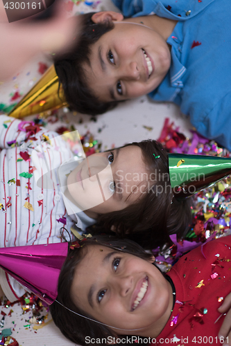 Image of kids  blowing confetti while lying on the floor