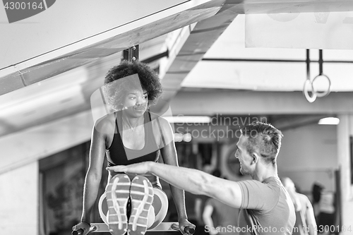 Image of black woman doing parallel bars Exercise with trainer