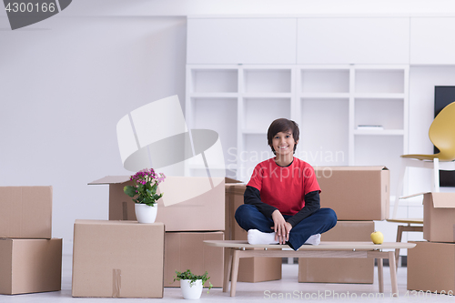 Image of boy sitting on the table with cardboard boxes around him