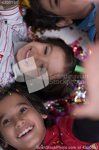 Image of kids  blowing confetti while lying on the floor