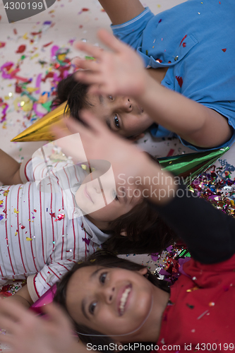 Image of kids  blowing confetti while lying on the floor