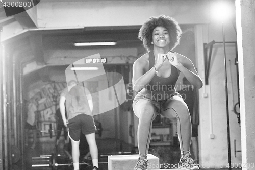 Image of black female athlete is performing box jumps at gym