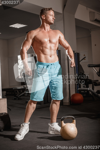 Image of Muscular bodybuilder guy doing exercises with weight in gym