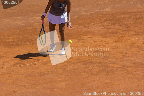 Image of A woman tennis player preparing to serve in tennis cort