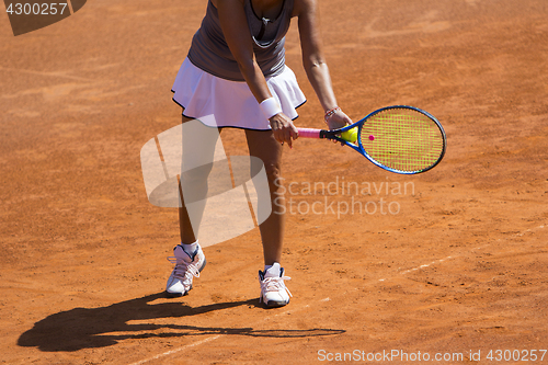 Image of A woman tennis player preparing to serve in tennis cort