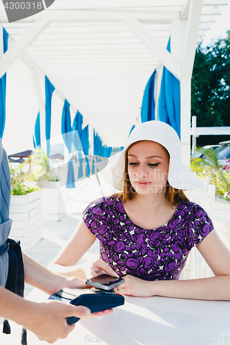 Image of Smiling woman paying with smartphone