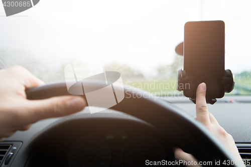 Image of Man behind wheel with smartphone