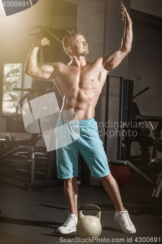 Image of Muscular bodybuilder guy doing exercises with weight in gym