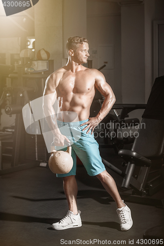 Image of Muscular bodybuilder guy doing exercises with weight in gym