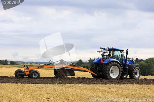 Image of Farmer Works With New Holland Tractor and Leveller