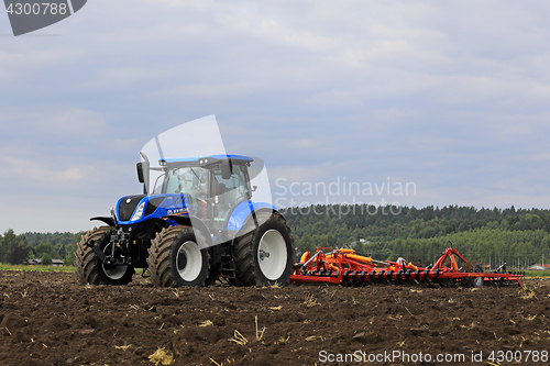 Image of New Holland Tractor and Potila Harrow on Field