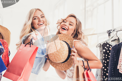 Image of The two young pretty girls looking at dresses and try on it while choosing at shop