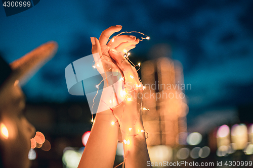 Image of Beautiful young woman smiling and talking garlands of lights at city