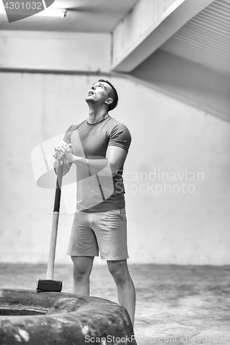 Image of man workout with hammer and tractor tire