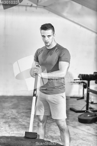 Image of man workout with hammer and tractor tire