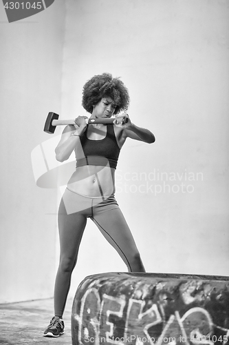 Image of black woman workout with hammer and tractor tire