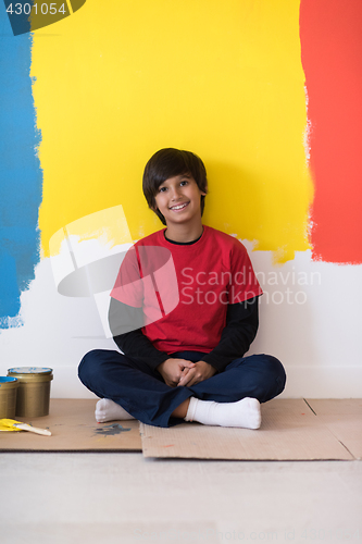 Image of young boy painter resting after painting the wall