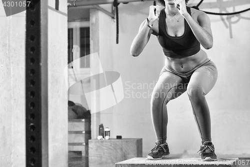 Image of black woman is performing box jumps at gym