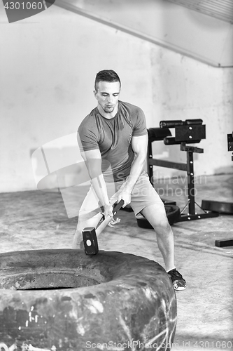 Image of man workout with hammer and tractor tire