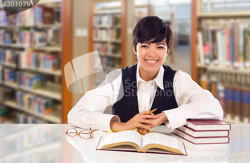 Image of Young Female Mixed Race Student In Library with Books, Paper and