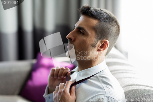 Image of businessman taking off his tie at hotel room