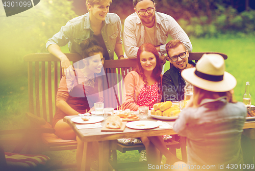 Image of happy friends having dinner at summer garden party