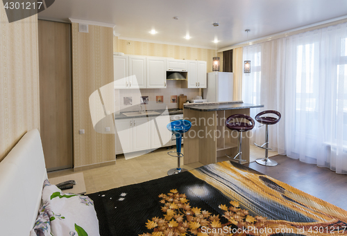 Image of Interior of a one-room apartment, view from the bed to the kitchen and a bar counter