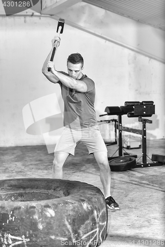 Image of man workout with hammer and tractor tire