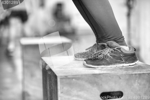 Image of black woman is performing box jumps at gym