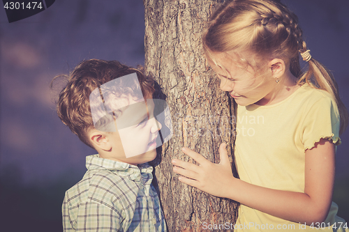 Image of Two happy children  playing near the tree at the day time.