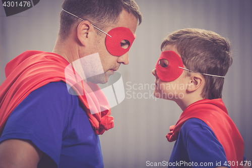 Image of Father and son playing superhero outdoors at the day time.