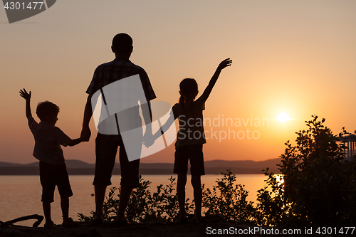 Image of father and children playing on the coast of lake