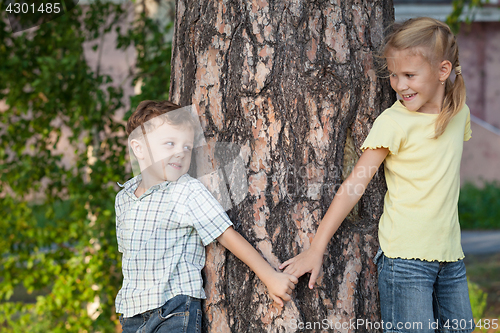 Image of Two happy children  playing near the tree at the day time.