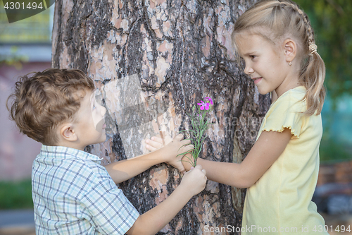 Image of Two happy children  playing near the tree at the day time.