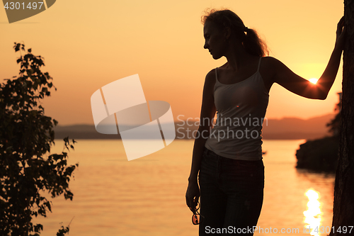 Image of Silhouette of woman who standing on the coast of lake