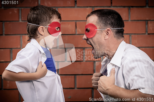 Image of Father and son playing superhero outdoors at the day time.