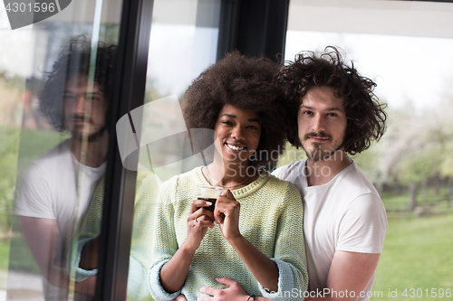 Image of happy multiethnic couple relaxing at modern home indoors