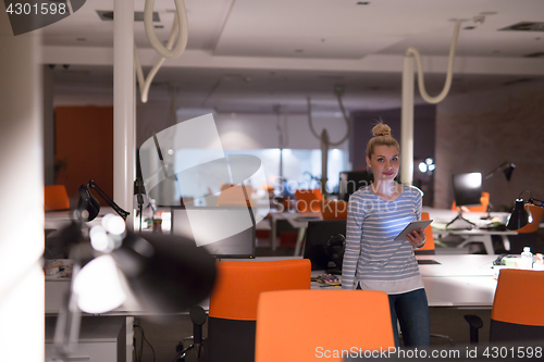 Image of woman working on digital tablet in night office