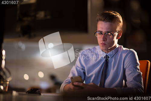 Image of man using mobile phone in dark office