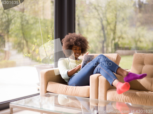 Image of young african american woman at home using digital tablet