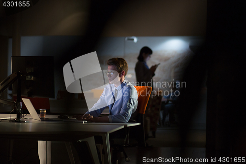 Image of man working on computer in dark office