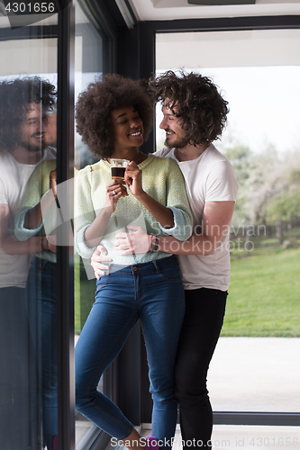 Image of happy multiethnic couple relaxing at modern home indoors