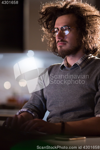 Image of man working on computer in dark office