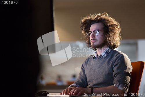 Image of man working on computer in dark office