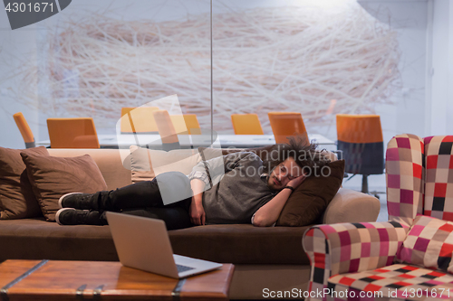 Image of man sleeping on a sofa  in a creative office