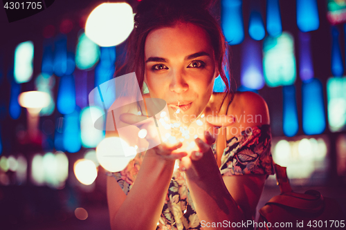 Image of Beautiful young woman smiling and talking garlands of lights at city